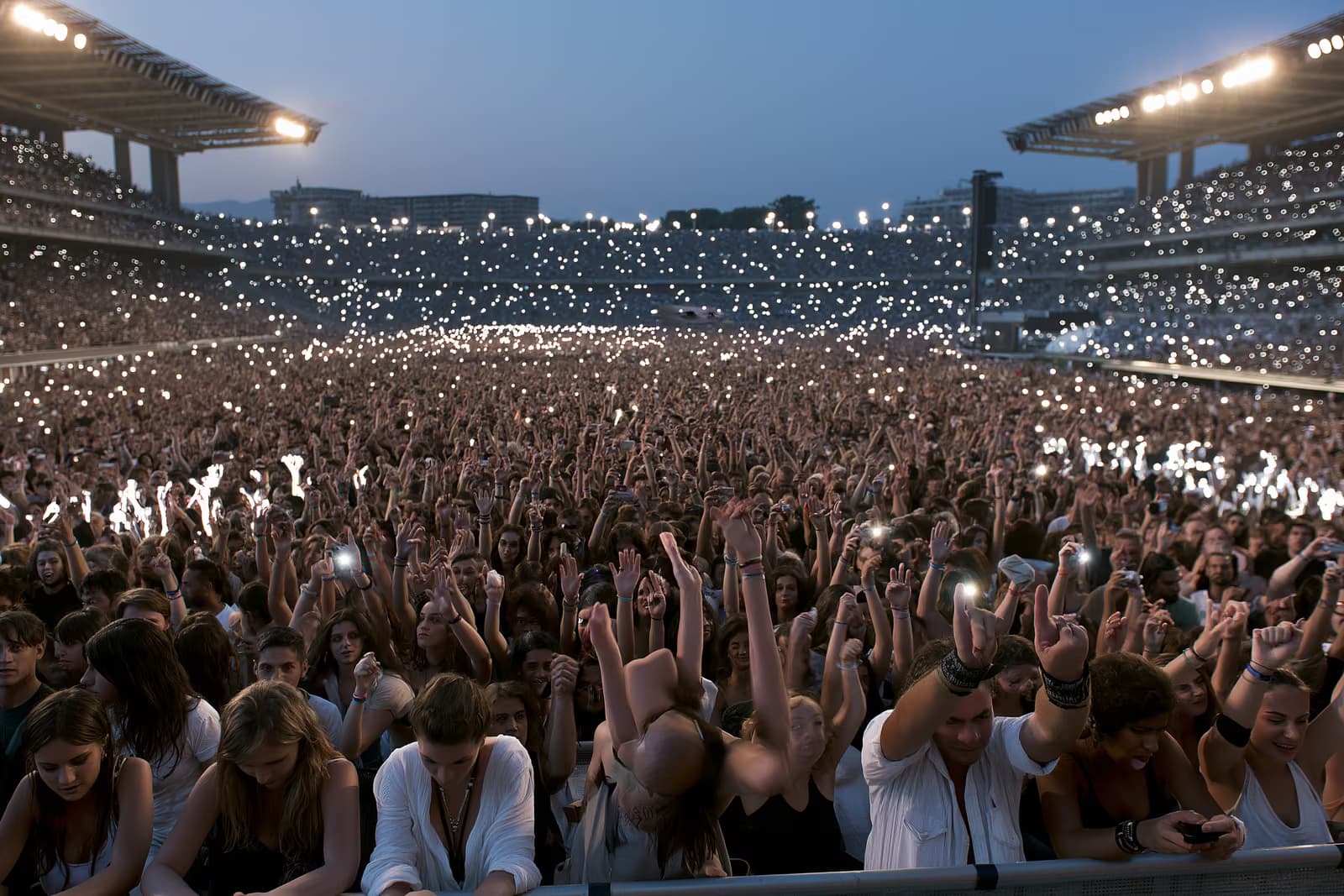 O mulțime mare pe stadion, luminată de lumina serii, în timpul unui concert de vară la München.