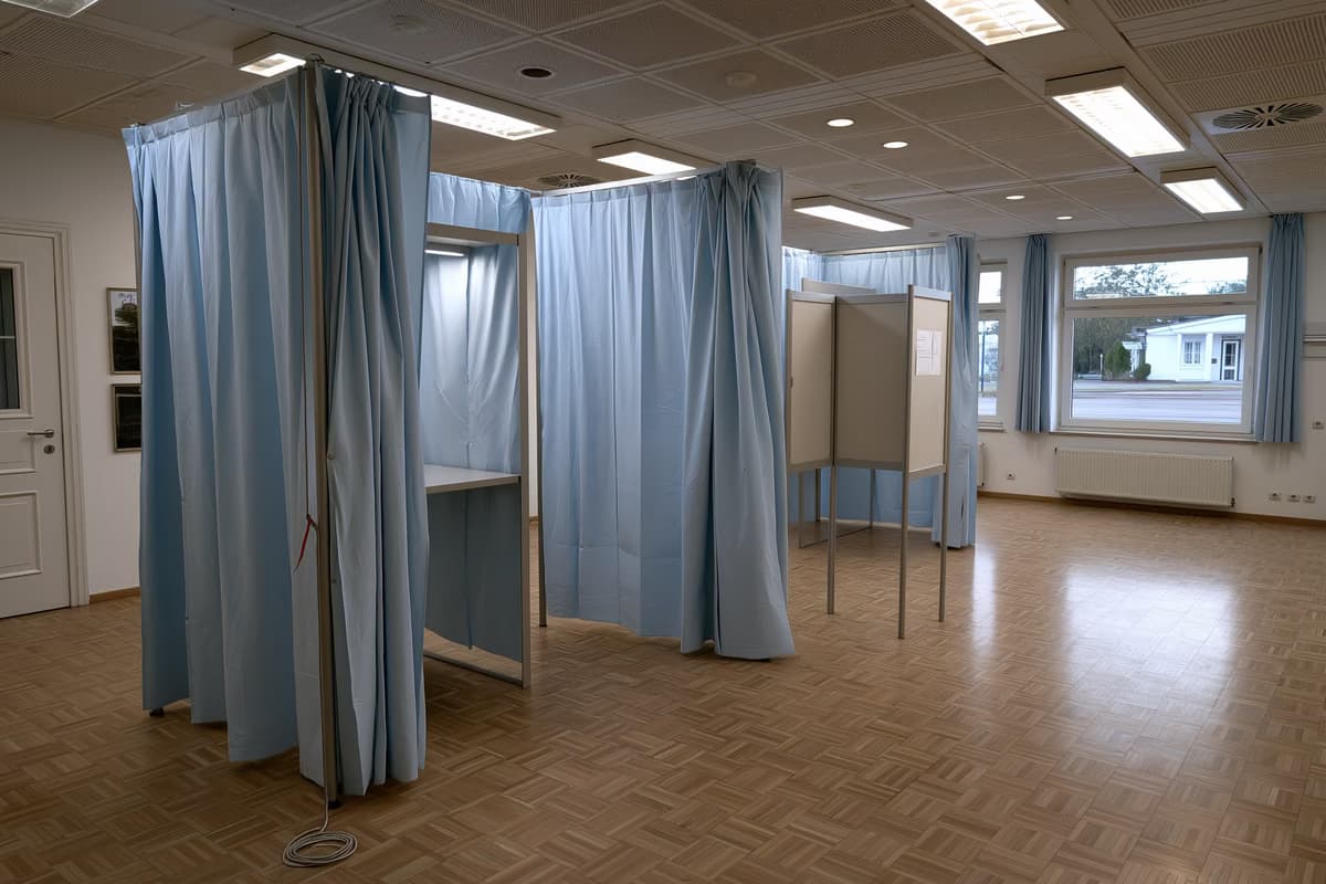 O cabină de vot goală cu un creion prins într-o sfoară într-o sală comunitară germană