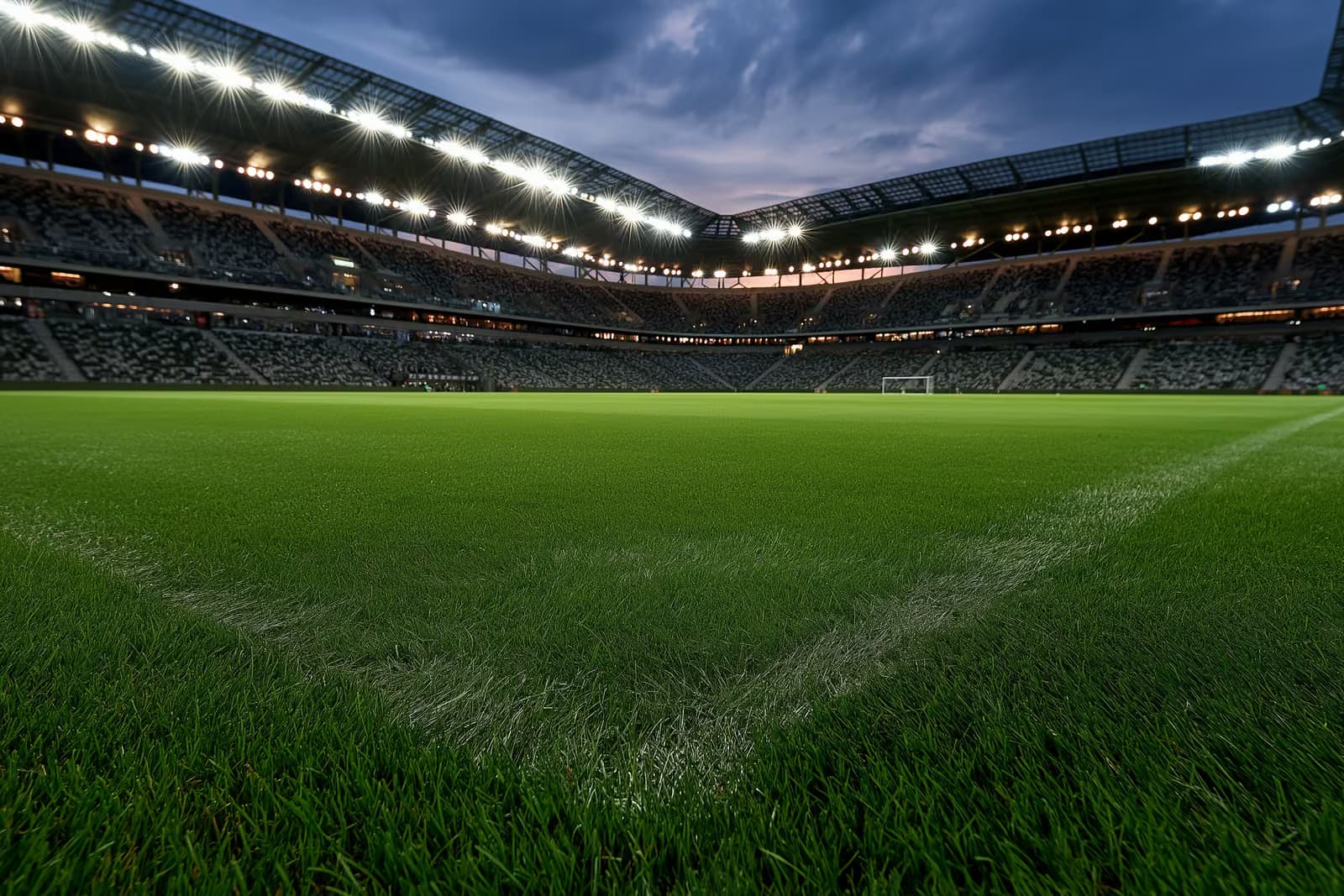 Un stadion de fotbal iluminat la amurg, înaintea unui meci de seară.