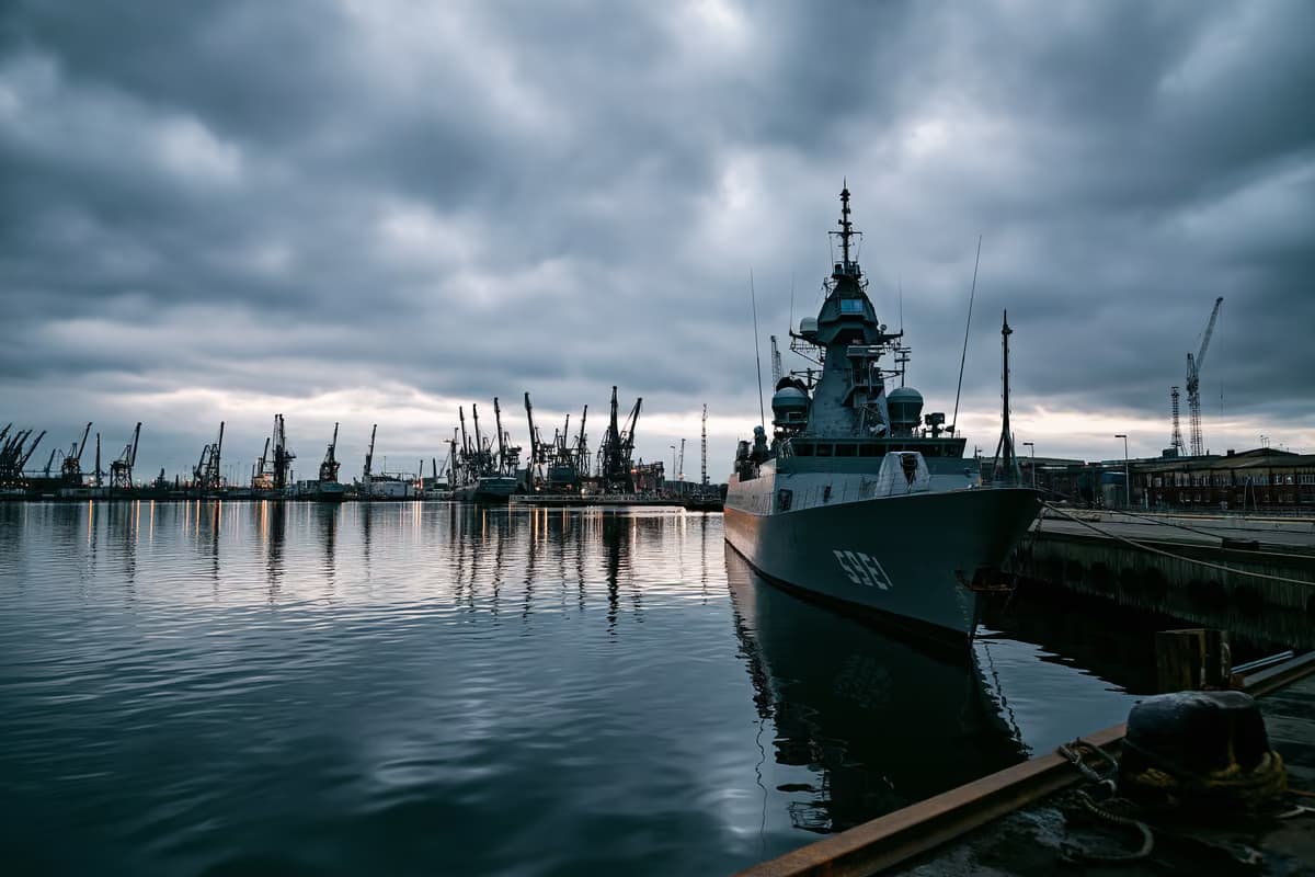 Un șantier naval gri sub un cer înnorat, sugerând investiții în apărare.